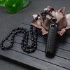 Natural black obsidian pendant necklace with Heart Sutra engraving on a wooden surface