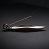 Brown ceramic leaf-shaped incense burner holding a stick of incense