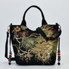 Black linen tote bag featuring gold and green embroidered peacock design with beaded strap accents