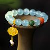 A close-up of a blue aquamarine bead bracelet with a yellow flower charm resting on a dark surface.