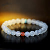 Close-up of a moonstone bead bracelet with red and turquoise accents on a dark surface