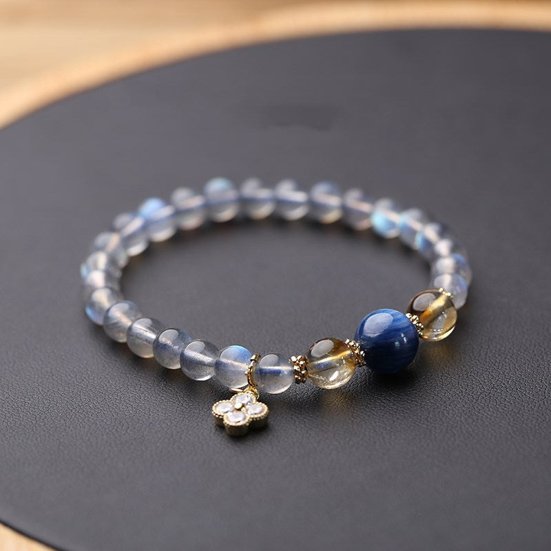 Natural moonstone bracelet with flower charm on a dark surface