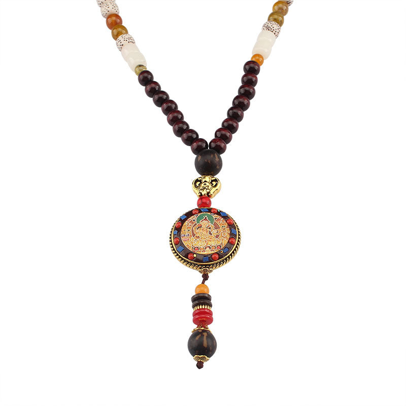 Close up of a round Thangka pendant hanging from a dark wood bead necklace