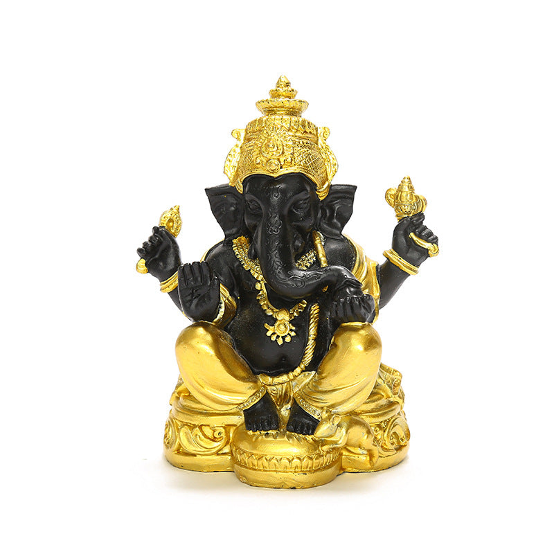 Black and gold-tone resin Ganesha statue sitting on a wooden surface
