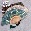 Open handheld bamboo folding fan with green background and white crane print