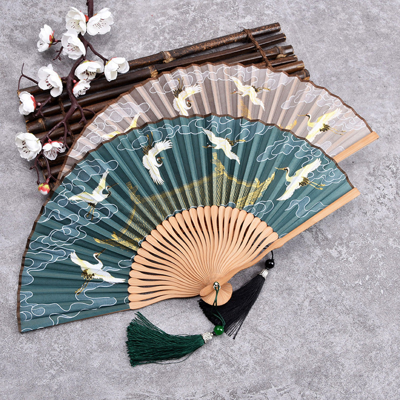 Open handheld bamboo folding fan with green background and white crane print