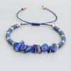 Close up of blue lapis lazuli stone chip bracelet with gold beads on white background