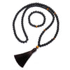 Matte black stone mala necklace with tiger eye beads and tassel on wood