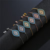 Gold-tone evil eye bracelet with blue and white zircons on a black display stand