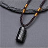 Close-up of a raw black tourmaline crystal pendant on a brown braided cord necklace