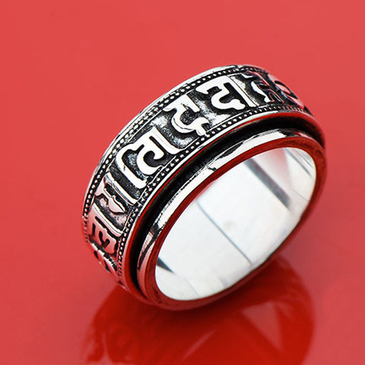 Silver tone titanium steel ring with Tibetan script on a red background