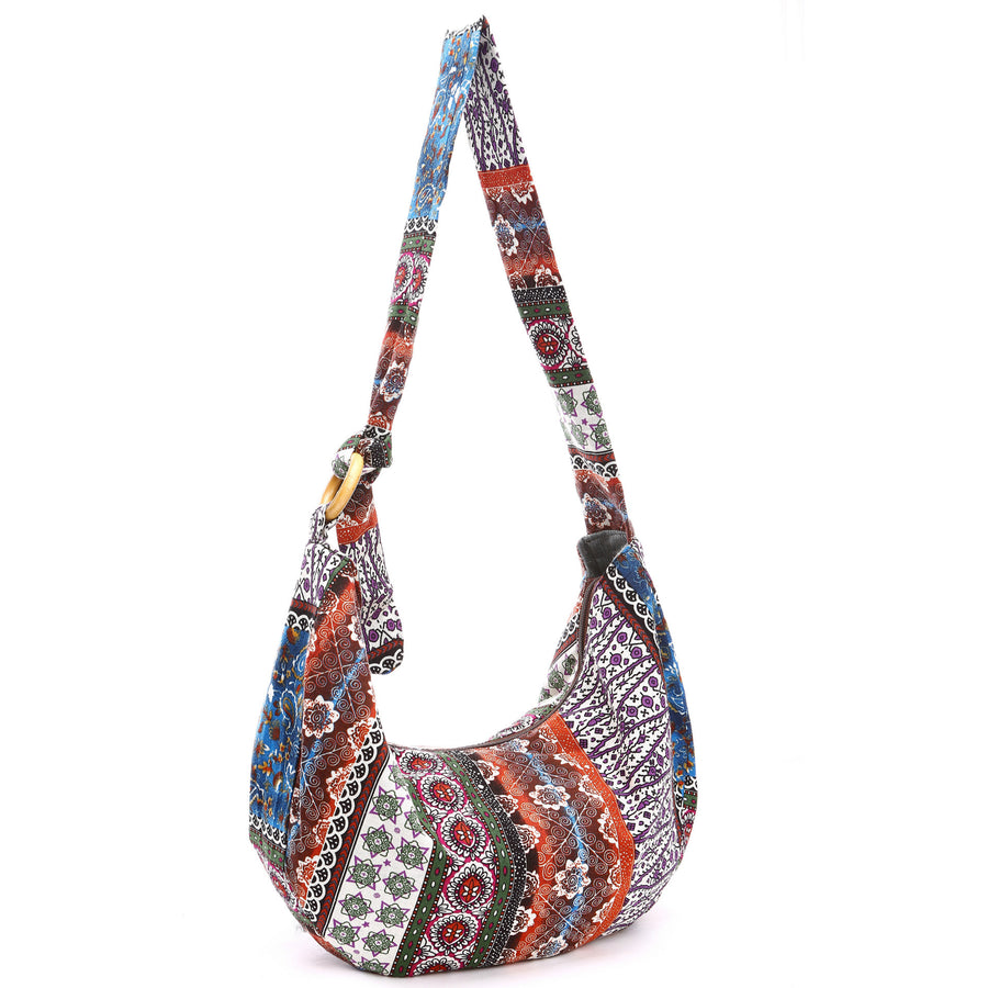 A colorful cotton shoulder bag with a floral pattern hanging against a white background