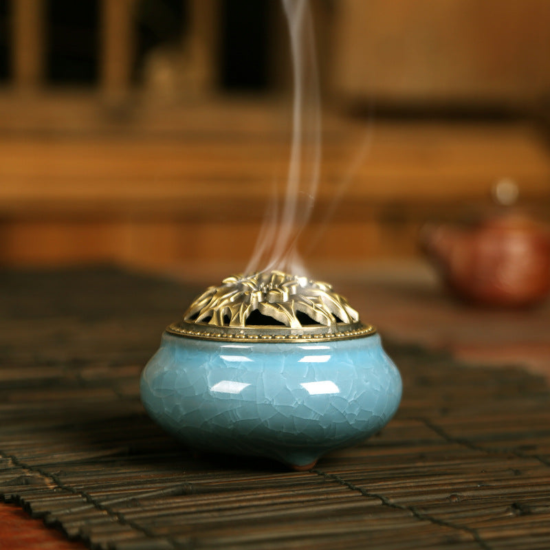 Blue ceramic incense burner with gold flower lid emitting smoke