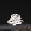 Close-up of a sterling silver ring with a white crystal plum blossom flower on a dark background