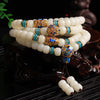 Coiled white bodhi seed mala bracelet with blue and gold cloisonné beads on a dark wooden stand