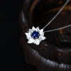 Close up of a silver lotus flower pendant with a blue lapis lazuli stone on a silver chain.