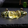 Close-up of a yellow citrine Pixiu charm on a beaded bracelet with green knots