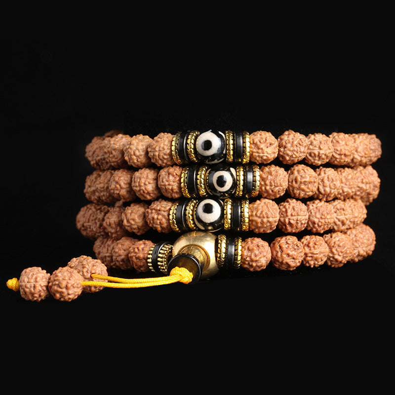 Close-up of a 108-bead rudraksha mala bracelet with black and white dzi beads on a dark background