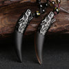 Natural ice obsidian wolf tooth pendant hanging on a brown braided cord with wooden beads