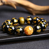 Close up of black bracelet with gold mantra script and a textured gold foil bead