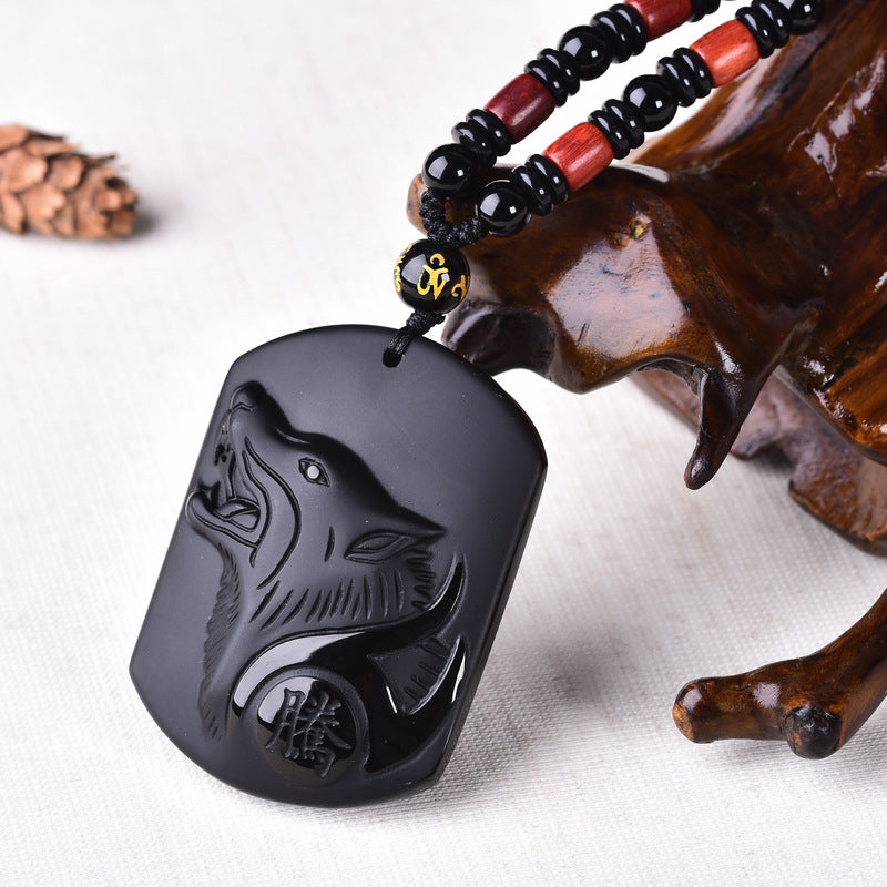 Black obsidian wolf pendant resting on a wooden display stand