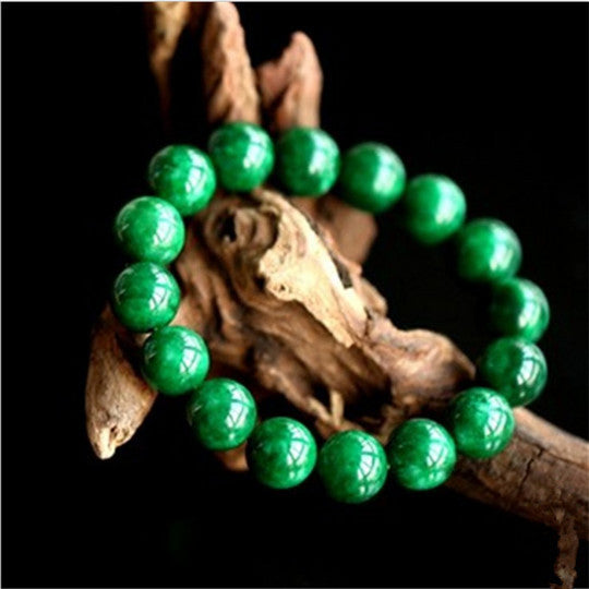 Green jade bead bracelet resting on driftwood