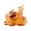 Amber colored glass dragon turtle figurine resting on a pile of coins
