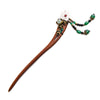 Close up view of a handmade wooden hairpin with a white flower and green beads on dark hair