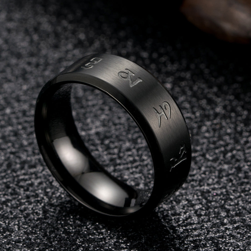 Close up of a black stainless steel ring with engraved Tibetan script