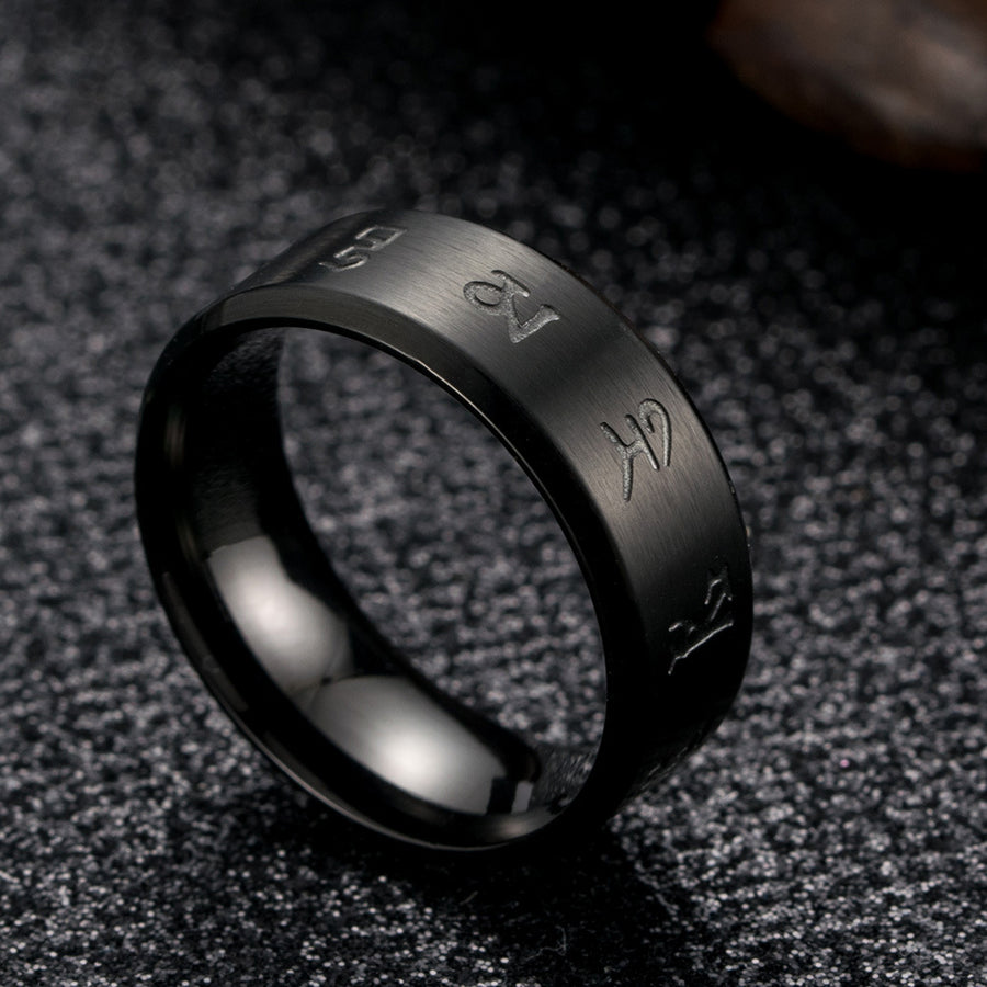 Close up of a black stainless steel ring with engraved Tibetan script