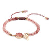 Pink faceted stone beaded bracelet with gold-tone charm on white background