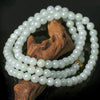 Coiled natural jade bead necklace resting on a piece of wood