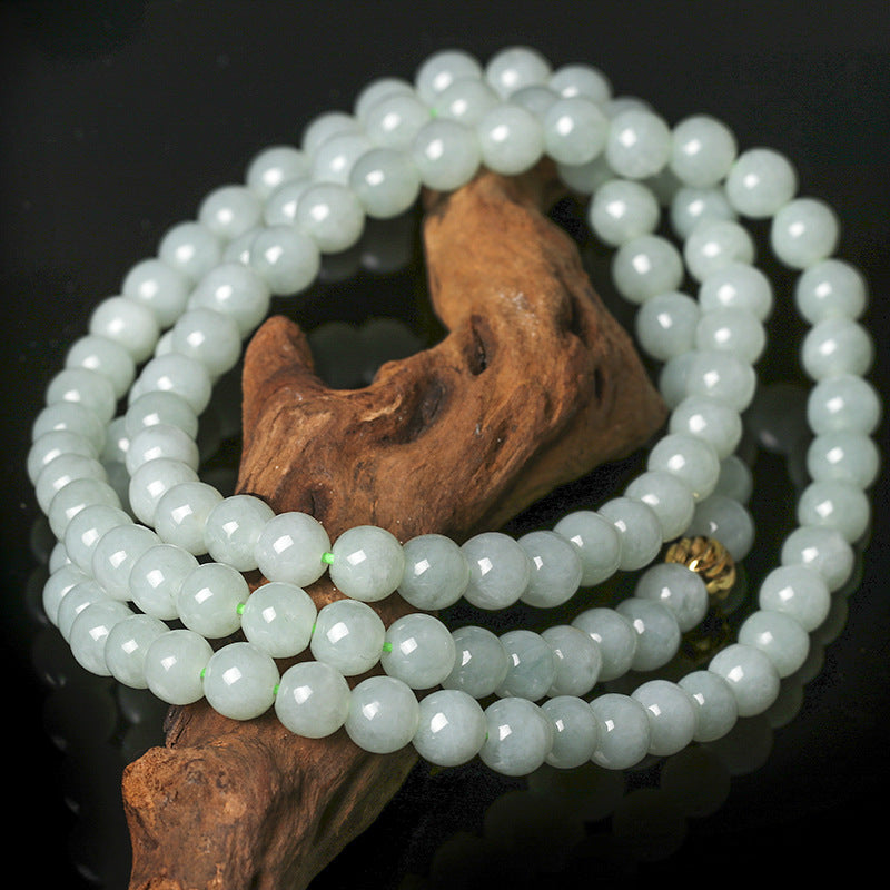 Coiled natural jade bead necklace resting on a piece of wood