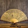 Close up of the light colored sandalwood fan showing detailed hollow carving work