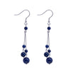 Pair of long sterling silver dangle earrings with blue lapis lazuli beads on a black background