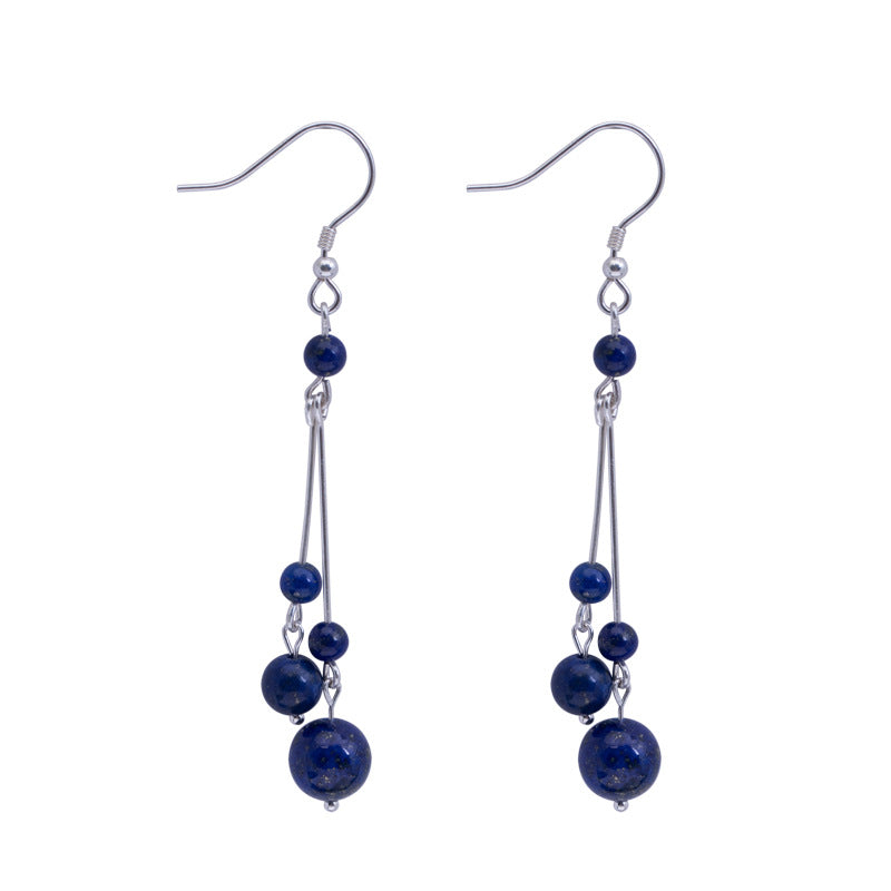 Pair of long sterling silver dangle earrings with blue lapis lazuli beads on a black background