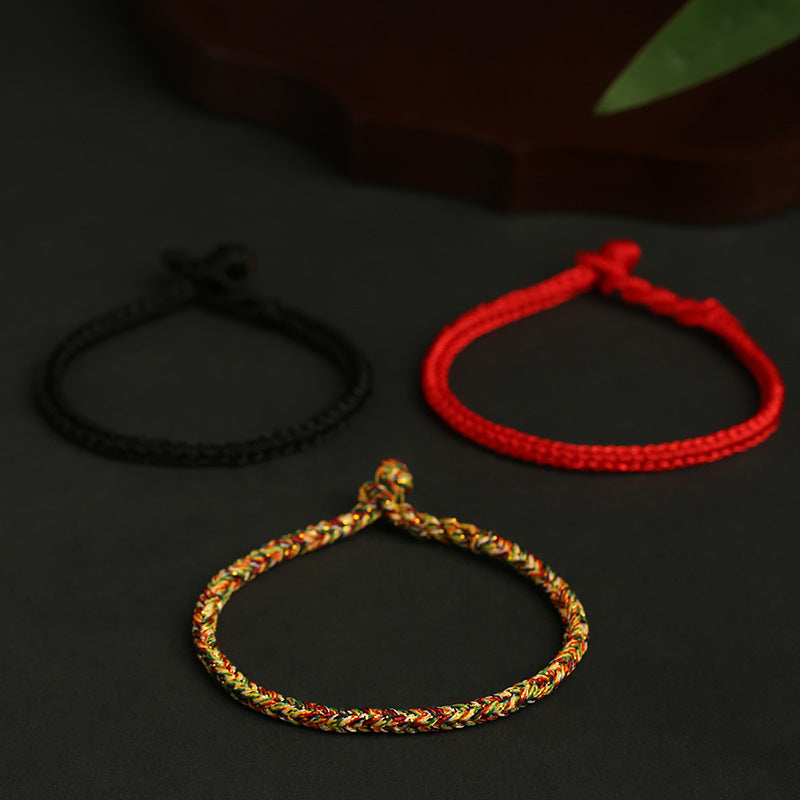 Three hand-braided bracelets in red, black, and multi-color with silver beads on a dark surface
