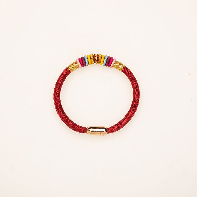 Close-up of a red braided bracelet with colorful knot details and a gold magnetic clasp on a white background