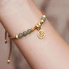 Close up of a jade beaded bracelet with a gold Fu charm on a wrist