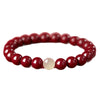 Single loop bracelet with round red cinnabar beads and one pale accent bead