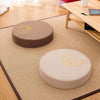 Round linen meditation cushion with gold lotus embroidery on a tatami mat