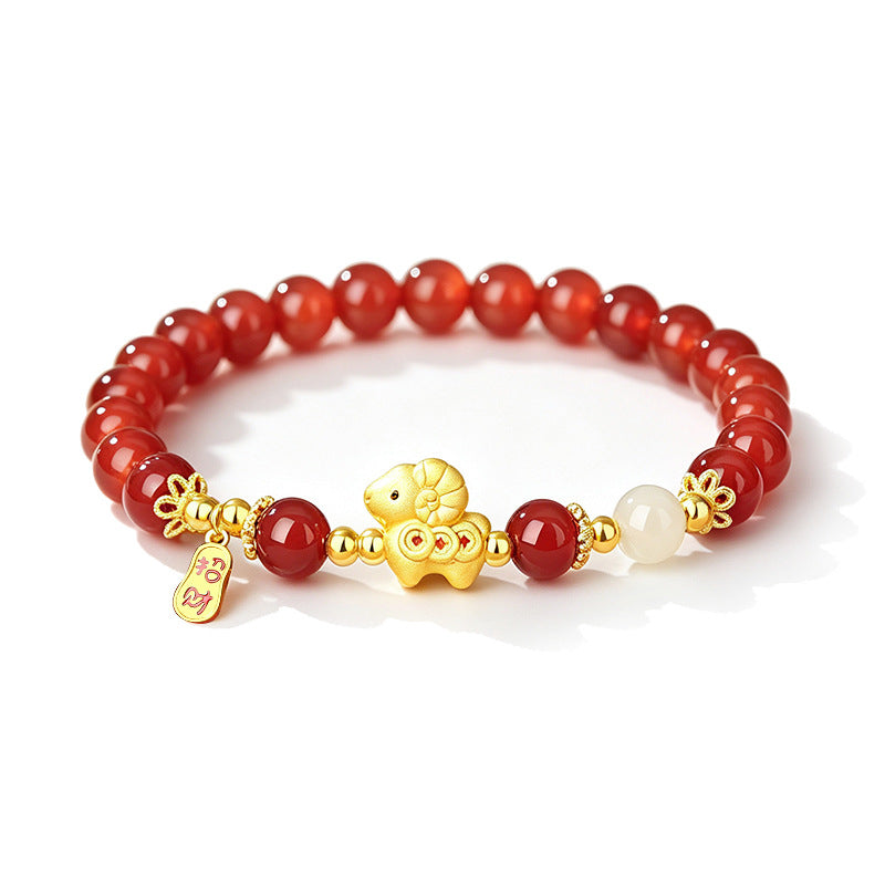 Close up of a red agate beaded bracelet with a gold sheep charm on a wrist