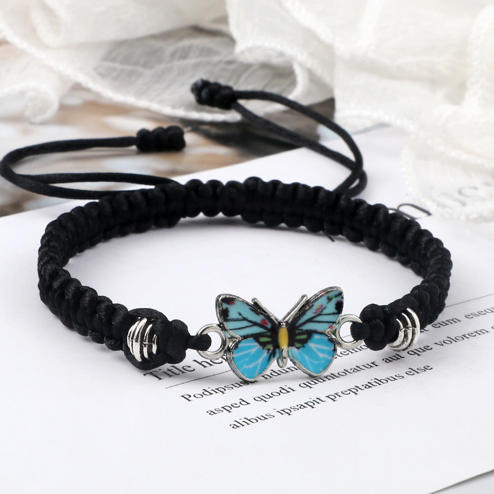 Close-up of a black woven bracelet with a blue butterfly charm