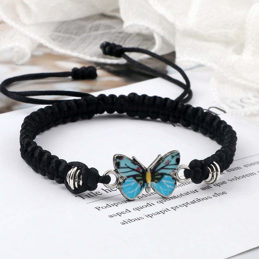 Close-up of a black woven bracelet with a blue butterfly charm