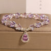 Close-up of a purple crystal bracelet with butterfly beads and a gourd pendant on a gold box.