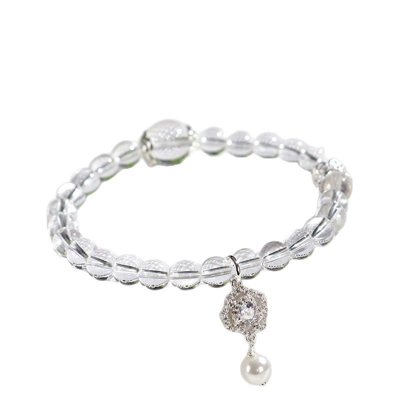 A clear white crystal bead bracelet with a small charm hanging from it