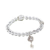 A clear white crystal bead bracelet with a small charm hanging from it