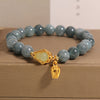 Blue water jade crystal bead bracelet with gold-tone gourd charm on a box