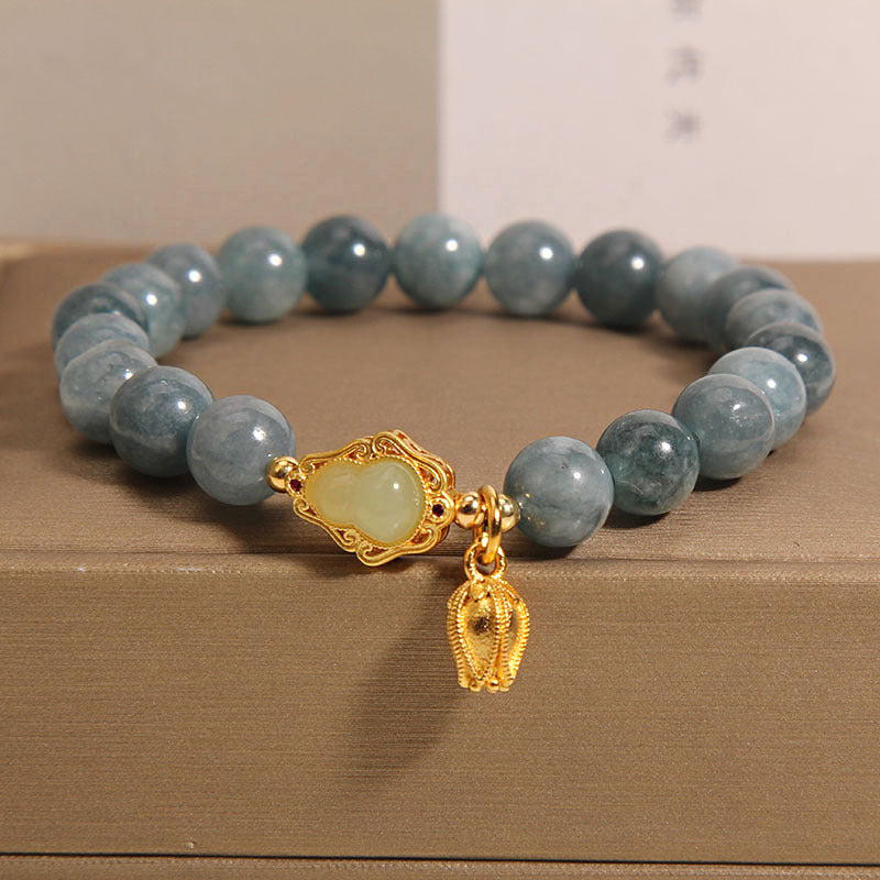 Blue water jade crystal bead bracelet with gold-tone gourd charm on a box