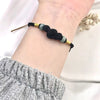 Close up of the black woven bracelet with jade beads on a wrist